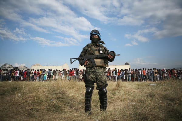 A United Nations peacekeeper stood guard in 2010 as residents of Cité Soleil in Haiti lined up for food and supplies after being displaced by an earthquake.